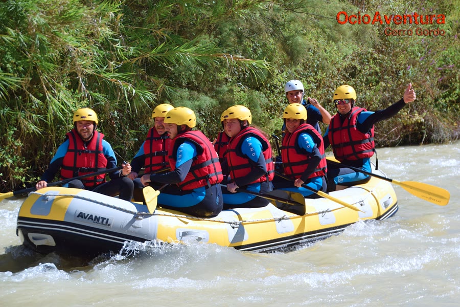 Equipo remando en la balsa de rafting